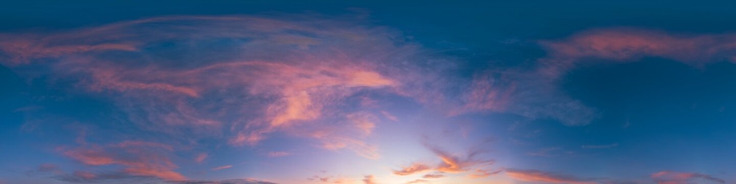 Sunset sky clouds featuring a panoramic view of colorful orange and purple cirrus wisps at dusk over a wide horizon