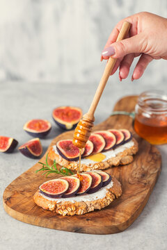 Preparing bruschetta with figs, honey and goat cheese for the breakfast