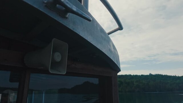 A megaphone for announcements on a boat while passing a green landscape on calm waters.