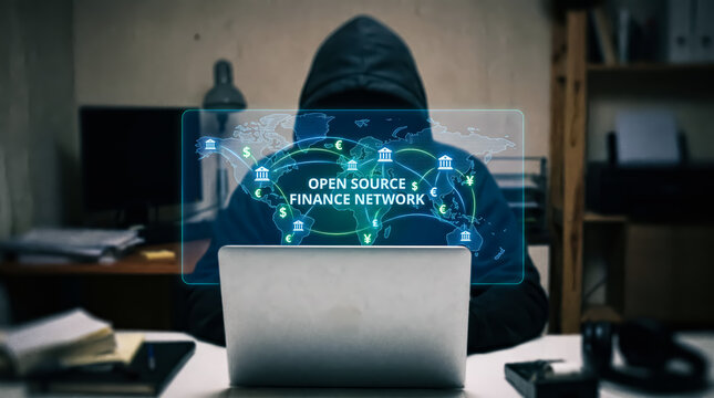 Anonymous person in a hoodie sitting in front of a laptop with a glowing holographic world map and financial symbols
