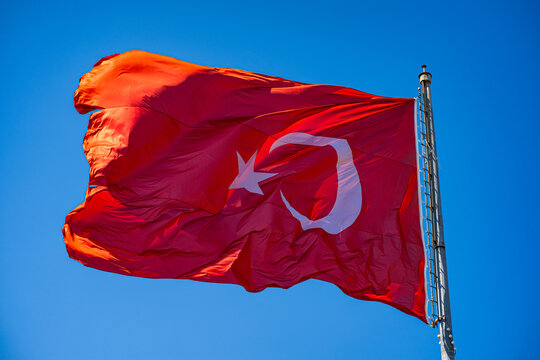 Close up view of Turkish flag waving against blue sky.