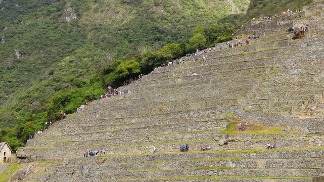 Tourists walk along the terraces of Machu Picchu. View of Machu Picchu.