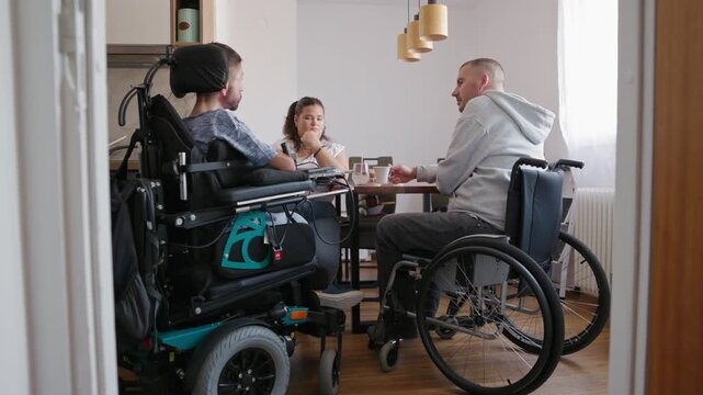 Two men with disabilities and a Personal assistant enjoying talking together and sharing experiences in the home environment.
