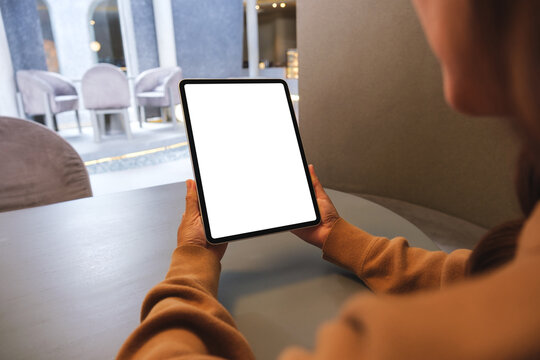 Mockup image of a woman holding digital tablet with blank white desktop screen in cafe