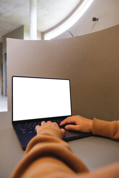 Vertical mockup image of a woman working and typing on laptop computer with blank white desktop screen