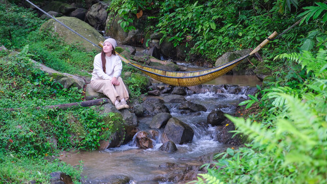 A woman sitting and relaxing by the creek
