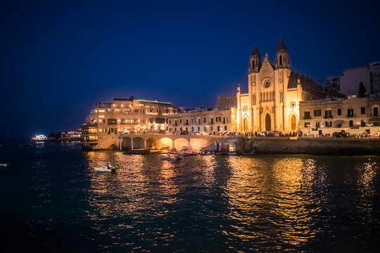 Facade of the Parish Church of Our Lady of Mount Carmel illuminated with reflections in the sea of ​​Balluta Bay, St. Julian's MALTA