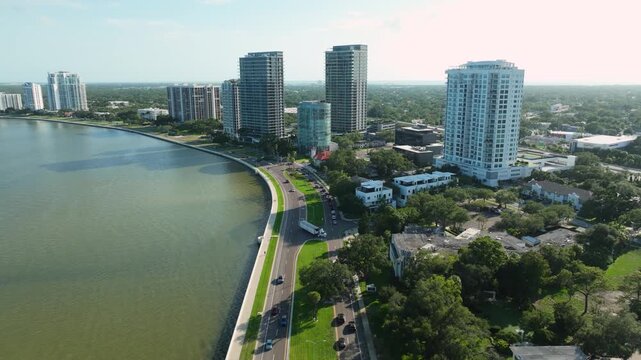 Aerial view of luxury waterfront high-rises rising above Bayshore Boulevard in Tampa's Hyde Park, with the downtown skyline glowing on the horizon.