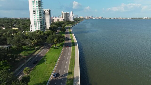 Aerial view of Bayshore Boulevard in Tampa's Hyde Park, featuring luxury high-rise condos along the seawall promenade with the downtown Tampa skyline in the distance.