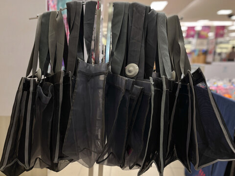Black reusable tote bags displayed together in a retail setting, representing sustainable shopping, everyday carrying, and eco-friendly lifestyle.