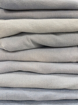 Neatly folded light gray fabric stacked in layers, showcasing soft textile texture and a clean neutral background for fashion and design concepts.