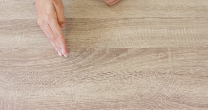 Close up of people talking to the camera, pointing at wooden table, hand indicating specific spot on