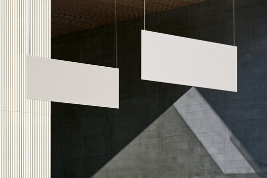 Two blank white rectangles suspended indoors by thin wires