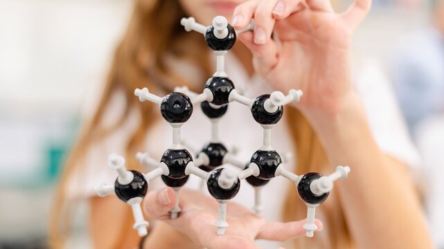 Person holding a molecular model in a science lab setting.
