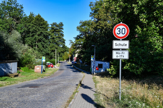 Tempo-30-Schild vor einer Schule an einer ruhigen Wohnstra&szlig;e. Schulweg, Verkehrssicherheit, Geschwindigkeitsbegrenzung, Kinder, R&uuml;cksichtnahme und kommunale Verkehrsberuhigung.