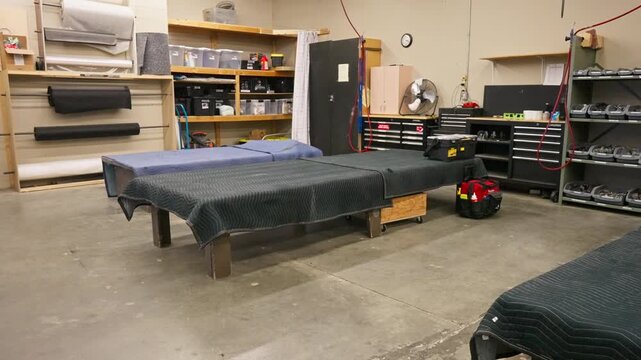 Automotive upholstery workshop interior with professional work tables and storage organization.