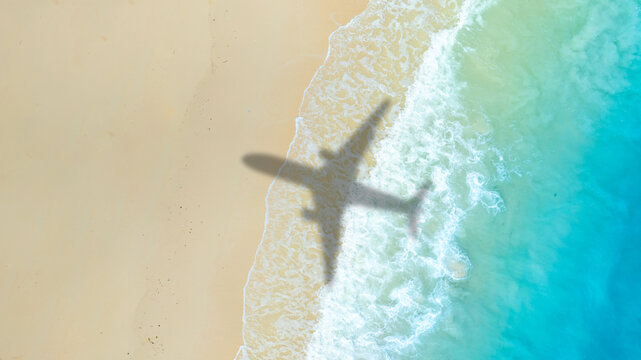 Aerial view of shadow passenger plane silhouette and sandy beach blue sea with waves at sea beach summer vacation sea travel concept	

