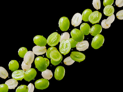 resh green grape slices and drops floating in midair on black background