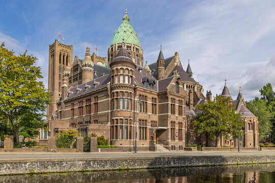 Haarlem, Netherlands: View of the Cathedral Basilica of Saint Bavo showcasing its grand brick architecture, copper dome, and surrounding trees under blue skies.