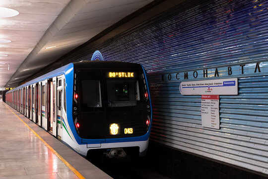 Kosmonavtlar metro station in Tashkent featuring green columns and ornate ceiling sculpture. Symmetrical underground hall with marble floors and commuters, ideal for travel and architecture.