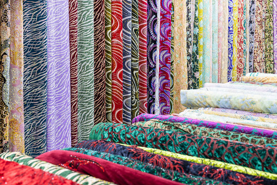 Colorful fabric bolts displayed at a traditional bazaar in Bukhara, Uzbekistan. Richly patterned textiles in vibrant colors hang and stack in abundance, ideal for travel and culture imagery.