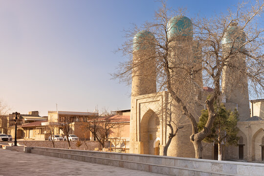 Chor Minor monument with four turquoise domes in Bukhara, Uzbekistan, bathed in warm golden light during winter. Ideal for travel guides, tourism brochures, and cultural heritage publications.