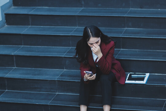 desperate Asian Korean business woman crying alone sitting on street staircase suffering stress and depression crisis being victim of mobbing or fired losing her job