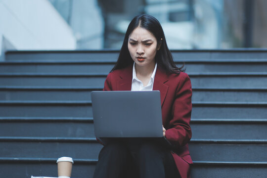 Asian woman in sitting at stairway outdoor have a stressed, after being laid off unemployed. Desperate be out of work.
