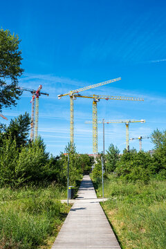 Construction cranes rise above an urban landscape and path in Nordbahnviertel Vienna Austria showing active development under clear blue sky in the city