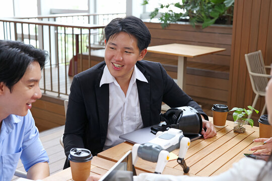 Asian Business Professionals Discussing Robotics and Virtual Reality at Outdoor Cafe