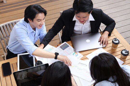 Asian Business Professionals Reviewing Financial Data During Outdoor Meeting