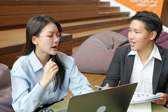 Young Asian Professionals Discussing Business Strategy with Laptop and Documents