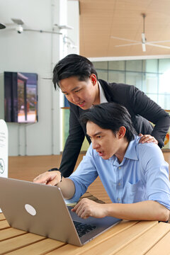 Two Asian Businessmen Looking at Laptop Screen with Concerned Expressions