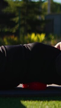 Mature women exercising outdoors on yoga mats, performing abdominal crunches and relaxation stretches on grass in sunny park wellness fitness routine