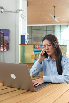 Professional Woman Talking on Smartphone While Working on Laptop Outdoors