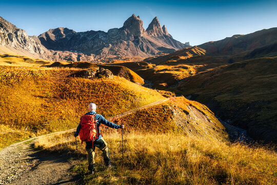 Solo Man Standing in Golden Grassland Rocky Valley with Famous Mountain Peak in Aiguilles d Arves France