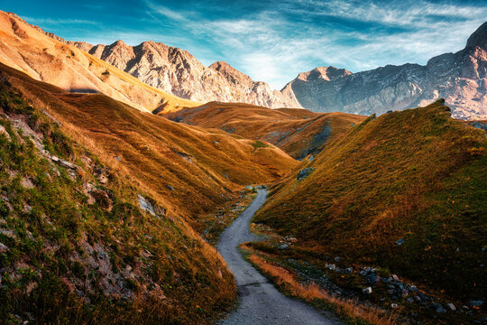 Mountain dirt path through autumn rocky valley landscape with mountain peak in remote wilderness