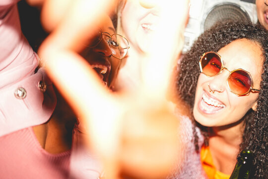Crazy women friends having fun at night time listening music outdoor and taking photos together - Party, nightlife and people lifestyle concept - UGC flash content - Main focus on right girl face