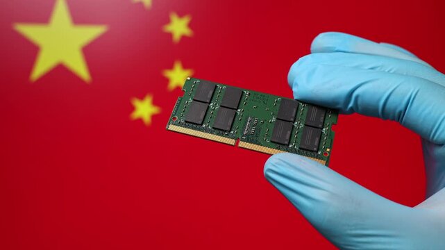 Close up view of hand in blue glove holding RAM memory microchip module. Chinese flag in blurred background. Concept of semiconductor shortage and artificial intelligence development in China.