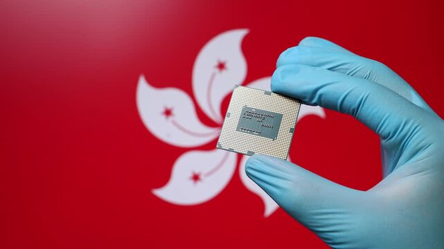 Close up view of hand in blue glove holding CPU microchip. Hongkongese flag in blurred background. Concept of semiconductor shortage and artificial intelligence development in Hong Kong.