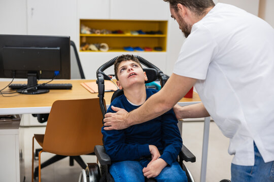 Orthopedist helping disabled child in wheelchair taking measurements