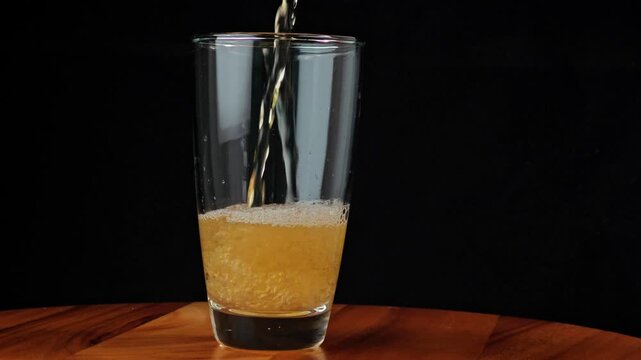 Beer pouring from bottle into glass with thick foam overflow.