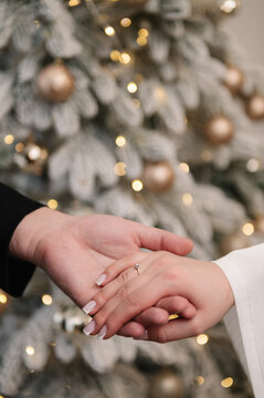 Marriage proposal, man holding woman's hand wearing a diamond engagement ring. Festive blurred background with bokeh lights. Romantic moment, love, engagement, promise. Closeup