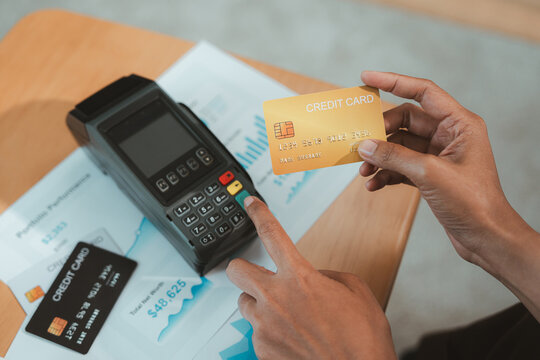 Financial advisor reviewing credit card payment for wealth planning with customer using payment terminal and document at wooden desk