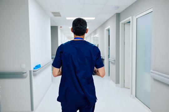 Health care worker walks through a hospital corridor to assist patients during a busy shift in the afternoon