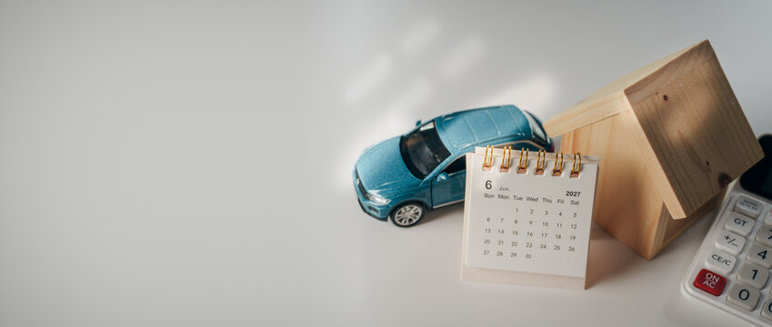 Car and wooden House Model, June Calendar with Calculator, June 2027 calendar, and calculator on white desk, concept of financial planning, loan for car and house purchase, and asset investment.