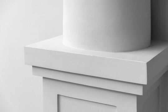 Close-up of a white architectural column base and pedestal showcasing clean lines, subtle texture and minimalist classical design. Neutral tones emphasize shape, geometry and architectural details