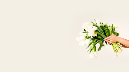 Woman holding a large bouquet of white tulips with copy space. Spring floral concept for flower delivery advertising, greeting cards, Women’s Day, Mother’s Day, romantic gifts and seasonal promotions. © Aigul Sabirova