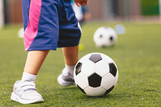 Close-Up of Young Child in Blue Shorts Dribbling Soccer Ball on Grass Field - Kids Football Training and Fundamental Motor Skills Practice