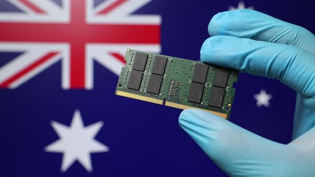 Close up view of hand in blue glove holding RAM memory microchip module. Australian flag in blurred background. Concept of semiconductor shortage and artificial intelligence development in Australia.